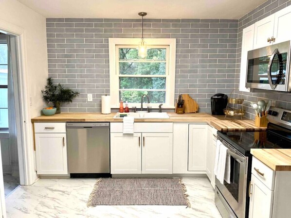 A modern kitchen with white cabinets, a built-in oven, and a microwave above the stove.