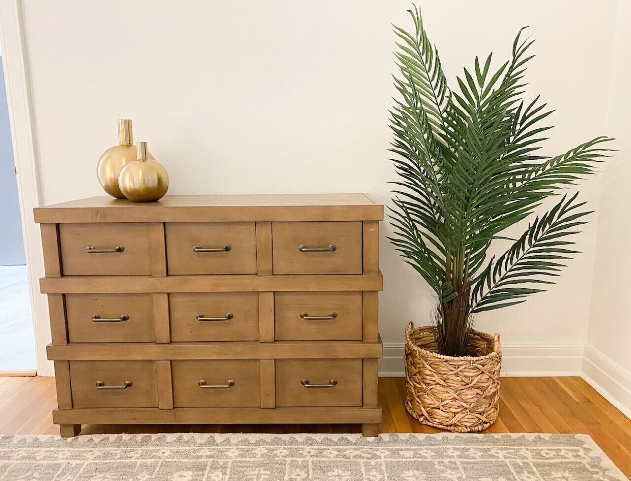 Une commode en bois avec de nombreux tiroirs et un panier en osier contenant une plante.