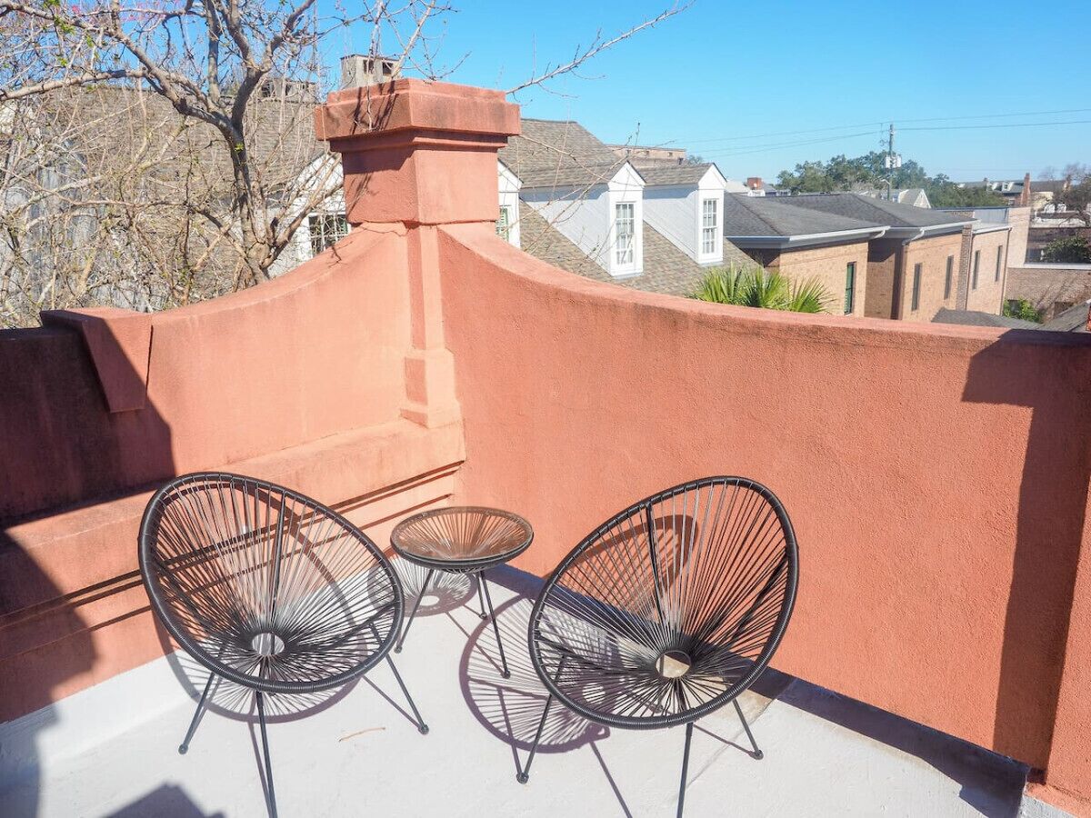 Terraza en la azotea con dos sillas de alambre negro y una pequeña mesa redonda.