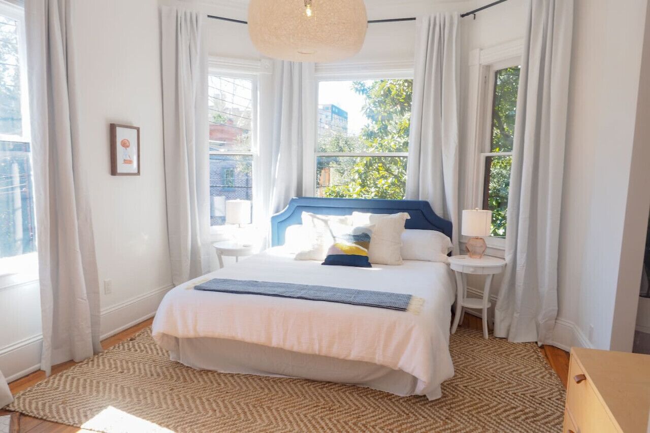 A neatly arranged bedroom with a bed, bedside tables, and a window with curtains.