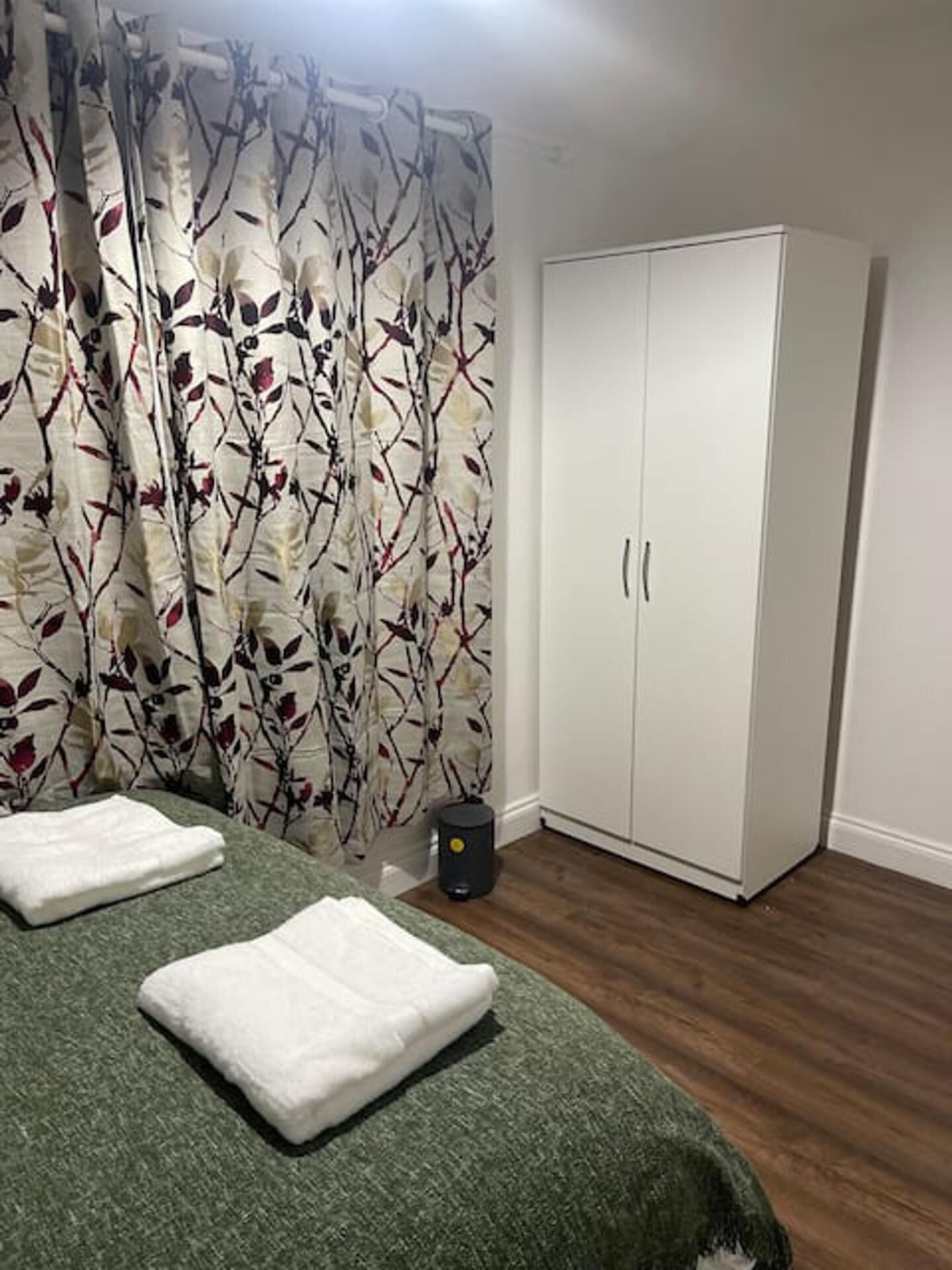 Ein Schlafzimmer mit einem Bett, einem Kleiderschrank und einem Vorhang mit Blättermuster.