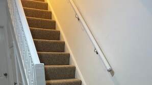 A staircase with carpeted steps and a white handrail. - Tms 3bdr Tilbury - Free Parking (Tilbury)