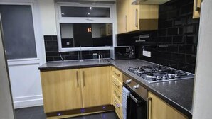 A compact kitchen with wooden cabinets, a gas stove, and a built-in oven. - Remarkable 3-bed House in Tilbury (Tilbury)