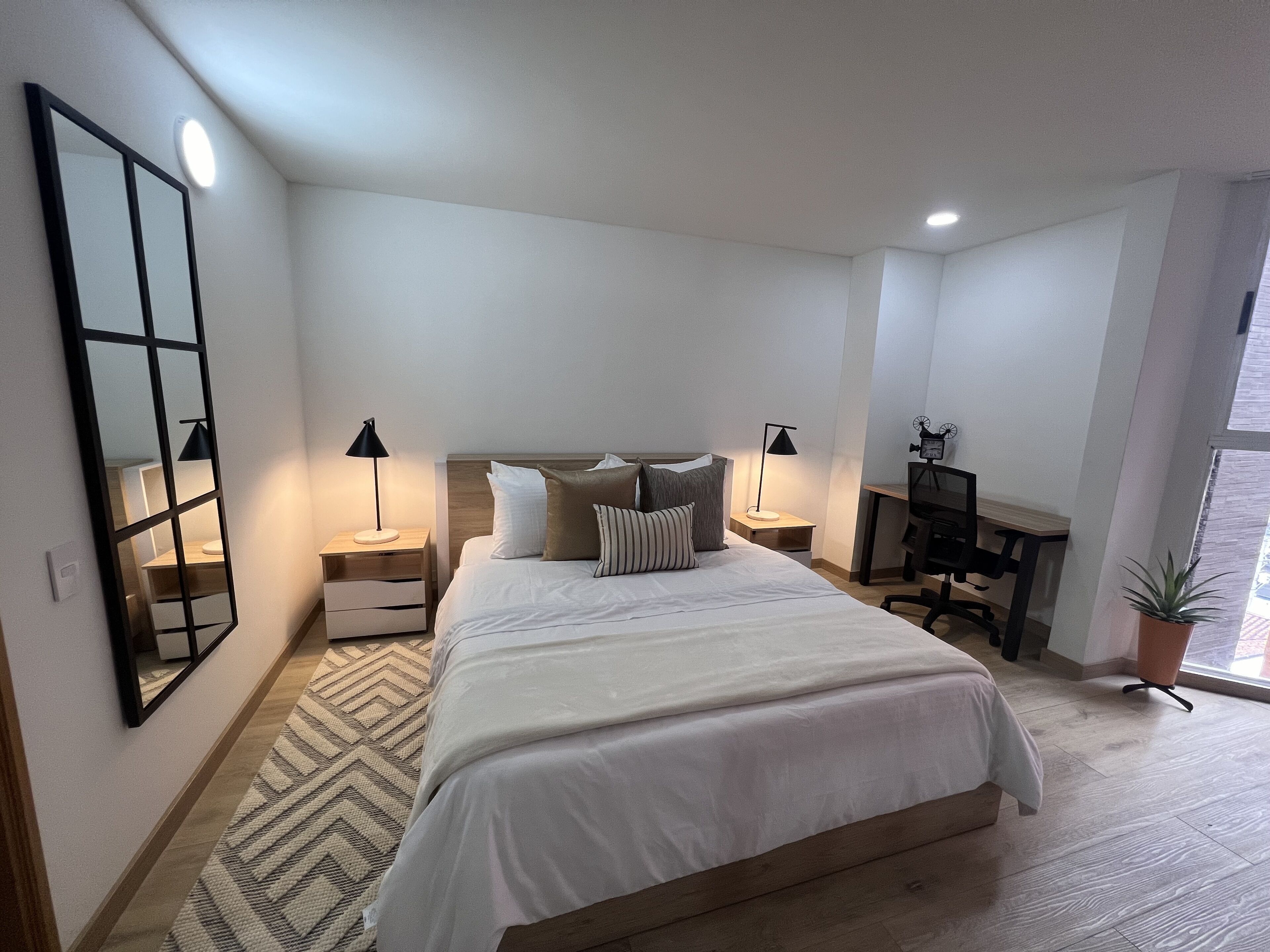 Een slaapkamer met een bed, nachtkastjes, een bureau en een stoel.