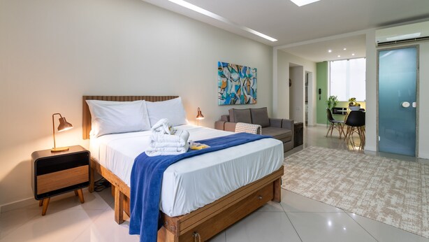 Un dormitorio moderno con una cama de madera, mesitas de noche, un escritorio y un comedor.