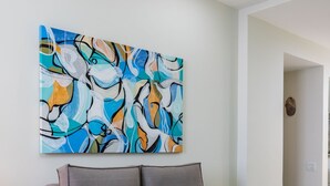 Una sala moderna con un sofá gris, un cuadro abstracto colorido y una pequeña mesita de madera.