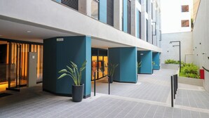 A modern hotel corridor with blue pillars, potted plants, and a visible retail store. - Pod by Wynwood House (Lima)