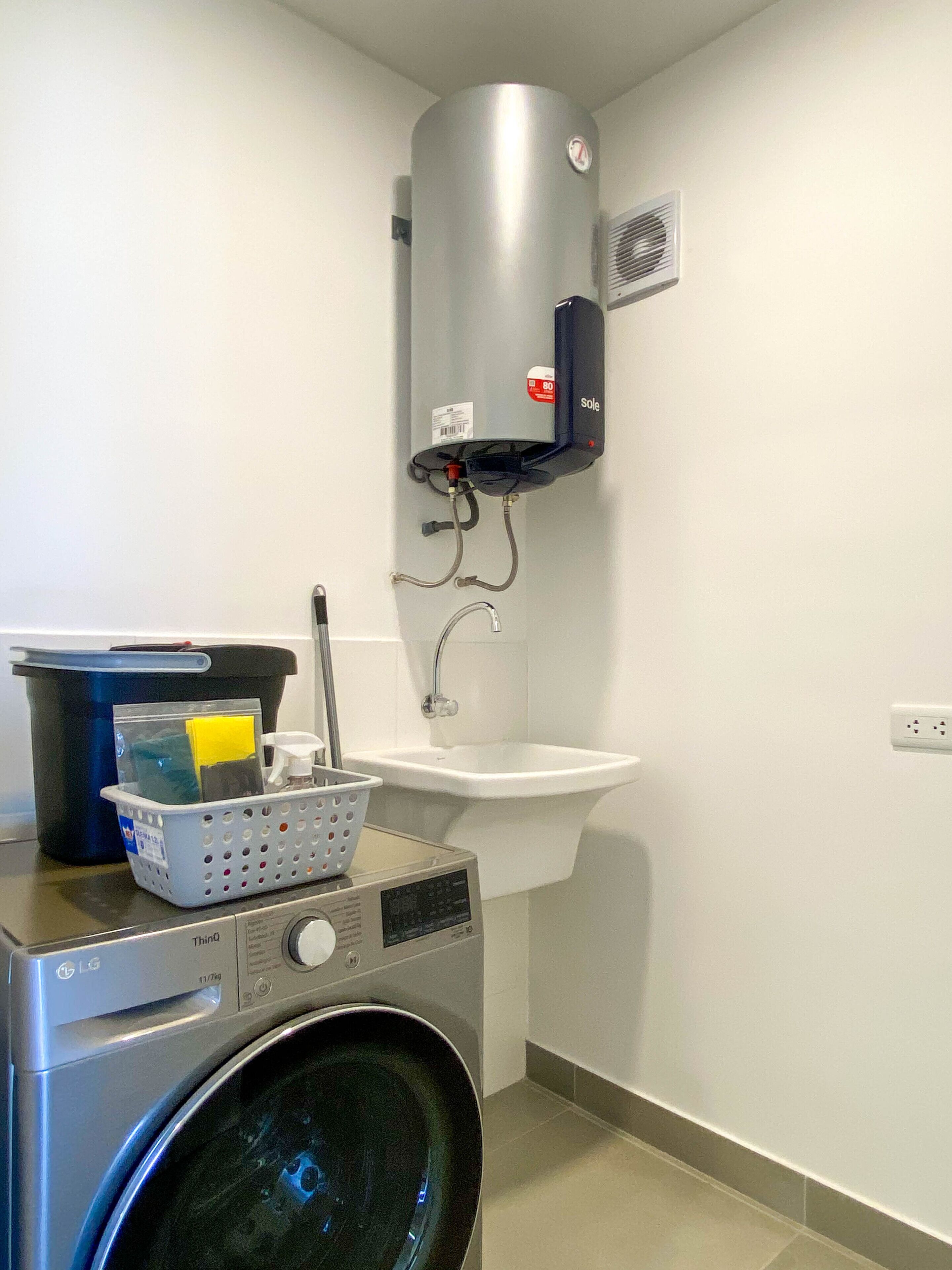 A laundry area with a washing machine, a water heater, and a sink.