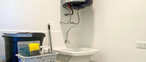A laundry area with a washing machine, a water heater, and a sink.