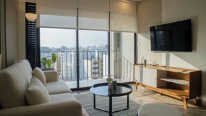 A modern living room with a sofa, a coffee table, and a TV mounted on the wall. - Pod by Wynwood House (Lima)