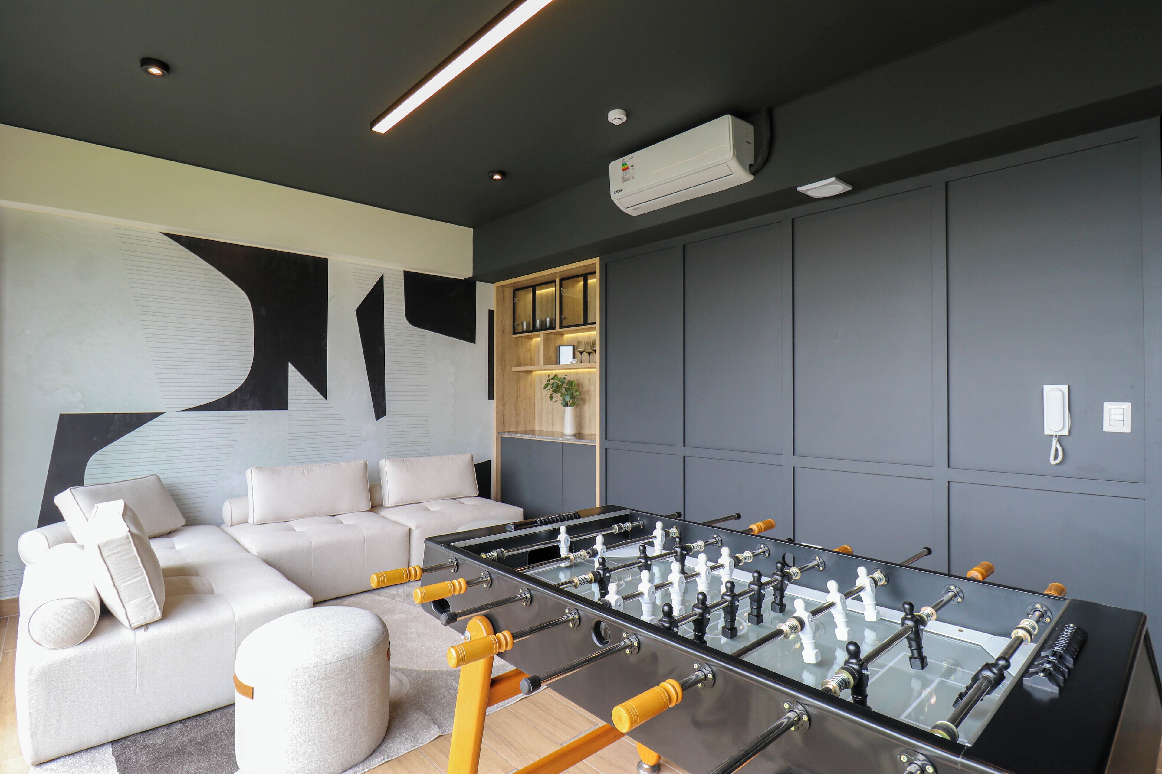 A modern living room with a foosball table, a sofa, and a wall-mounted cabinet.
