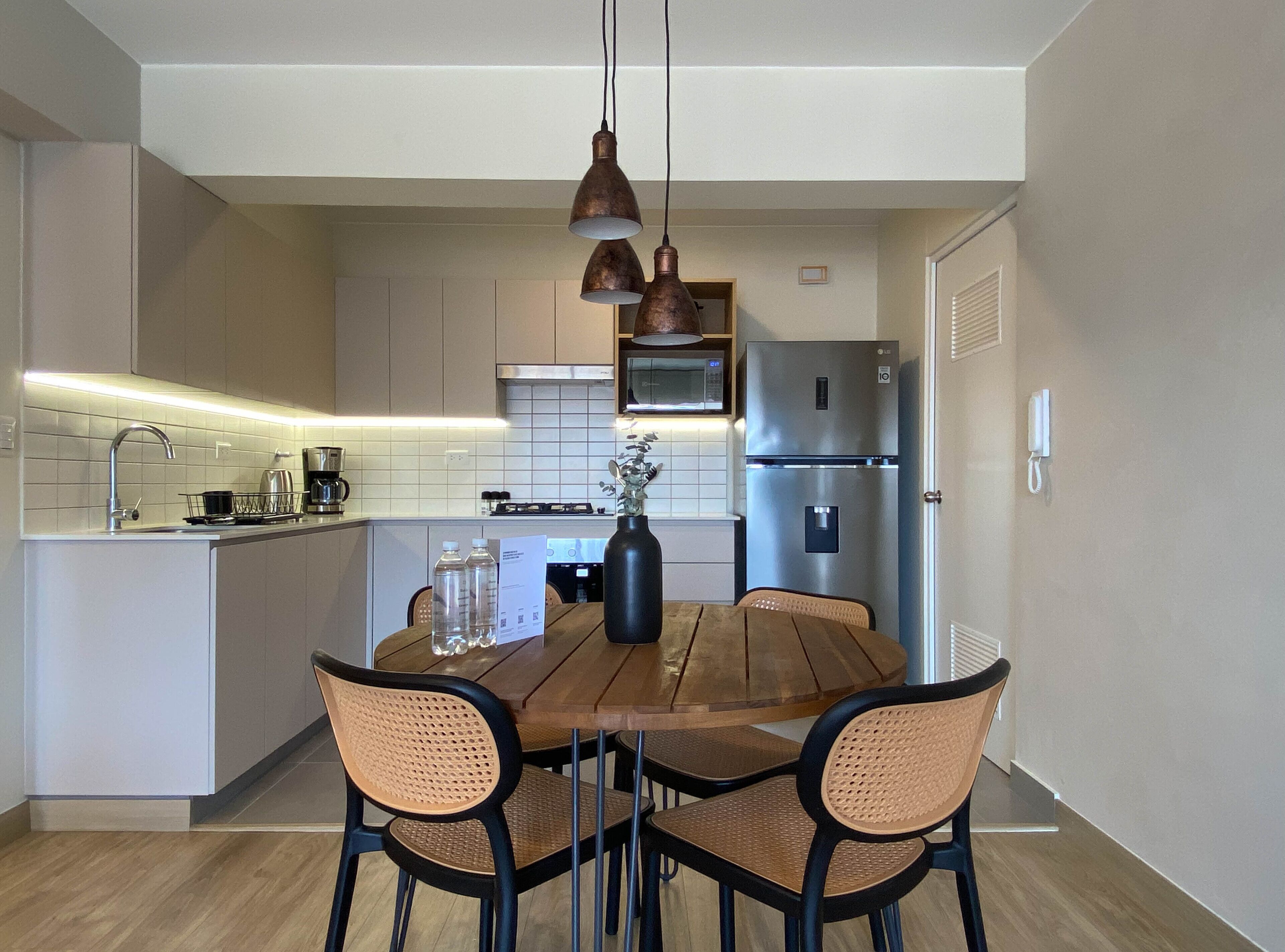 Eine moderne Küche mit einer zentralen Kochinsel, Edelstahlgeräten und einem Essbereich mit Holztisch und Stühlen.