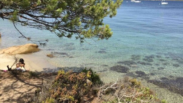 A beach with clear water, a rocky shore, and boats in the distance. - Brand new house in Sardinia -ultrafast internet (Laerru)