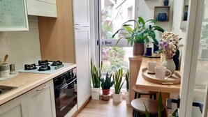 A modern kitchen with a stove, oven, and sink. There are potted plants and a dining area with chairs and a table. - Brand new house in Sardinia -ultrafast internet (Laerru)