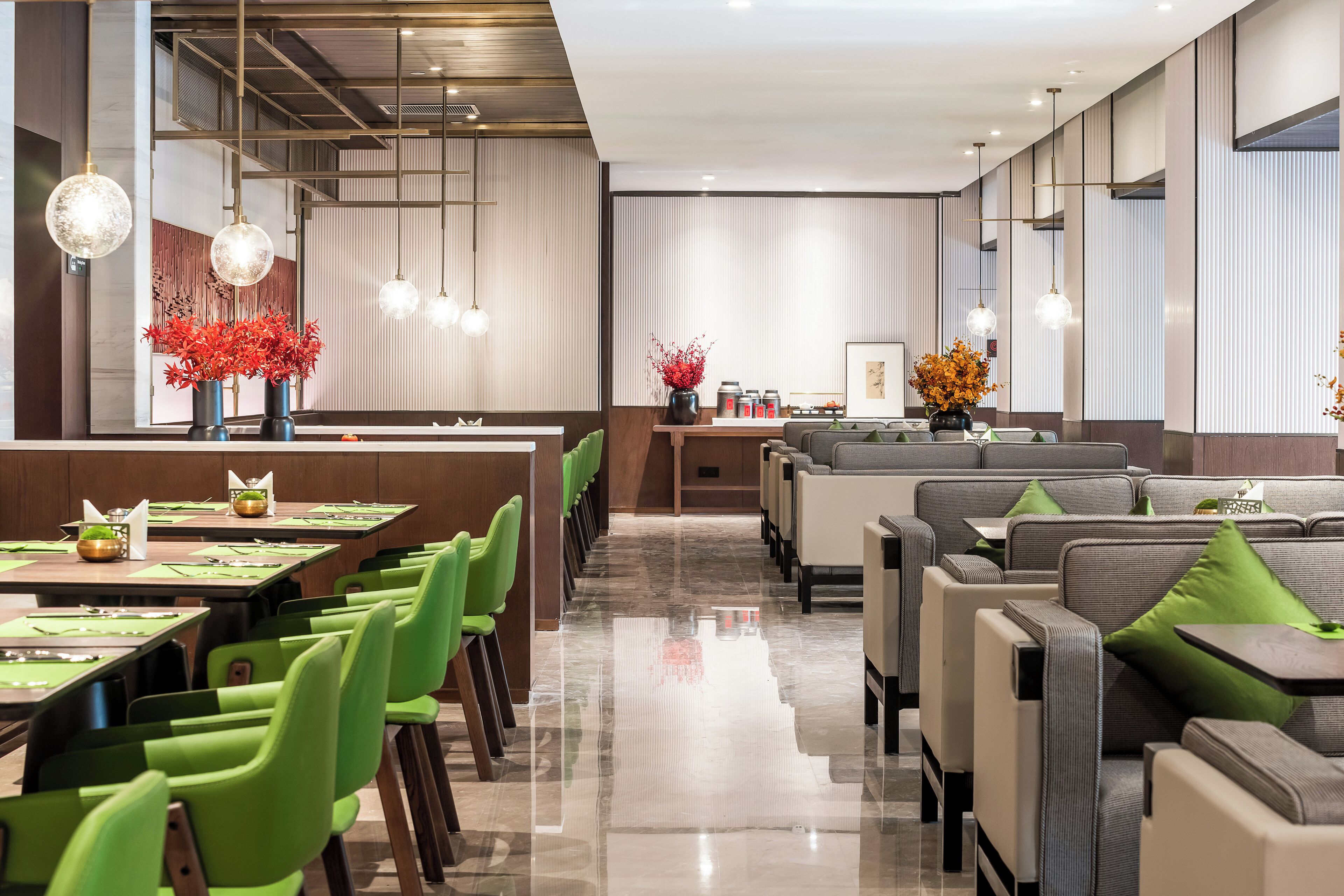 Un restaurant moderne avec des chaises vertes, un long comptoir et des luminaires suspendus.