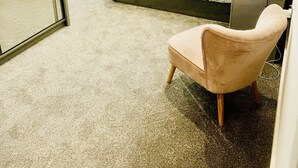 Ein Schlafzimmer mit einem Bett, einem Sessel, einer Heizung und einem Fenster mit Jalousien.
