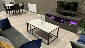 Ein modernes Wohnzimmer mit einer Couch, einem Couchtisch, einem Fernseher und einer Wand mit Muster.