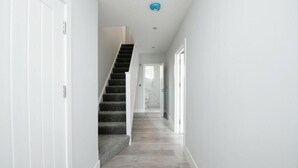 Ein moderner Flur mit Treppe, weißen Wänden und Holzboden.