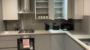 Eine moderne Küche mit Gasherd, Backofen und Mikrowelle. Eine eingebauten Regal mit Tassen und Tellern.