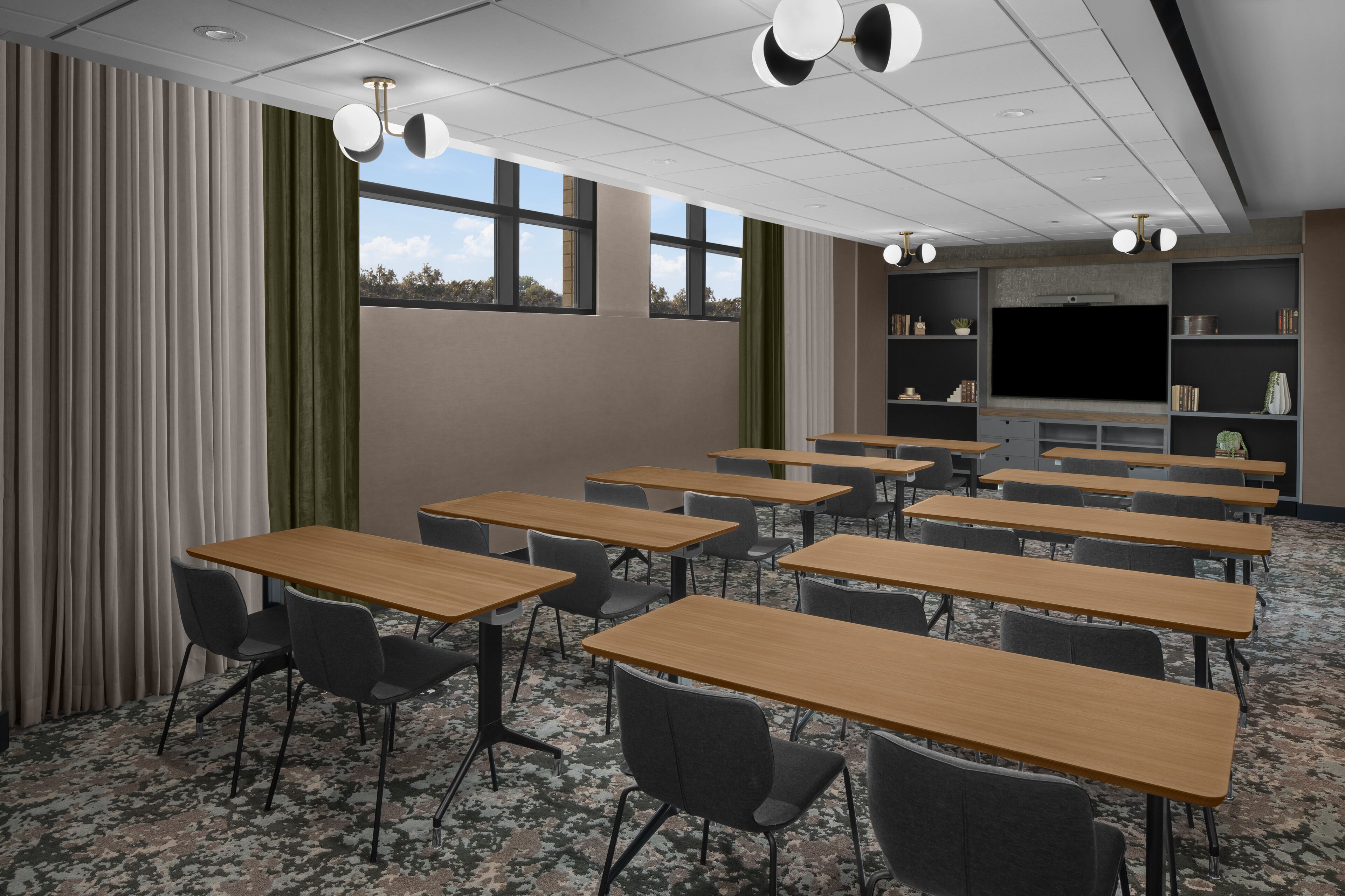Un salón de conferencias con varias mesas y sillas, una pantalla grande y estanterías con libros y objetos decorativos.