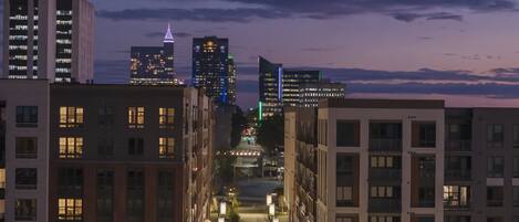 A nighttime cityscape with modern buildings, a well-lit street, and a clear sky.