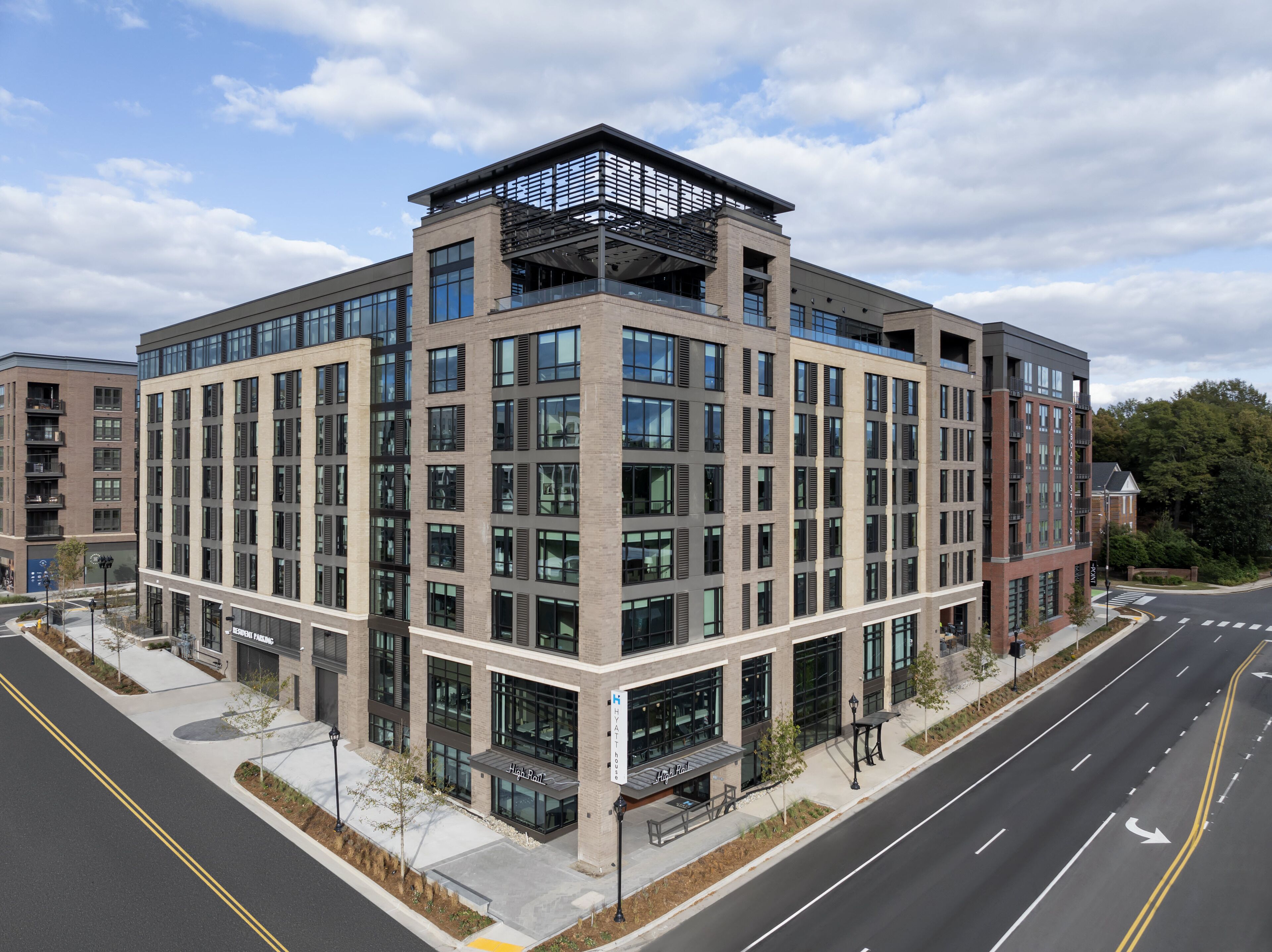 A multi-story hotel with a modern architectural design, featuring large windows and a rooftop terrace.