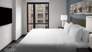 A hotel room with a large bed, a flat-screen TV mounted on the wall, a window with a city view, and a painting on the wall.