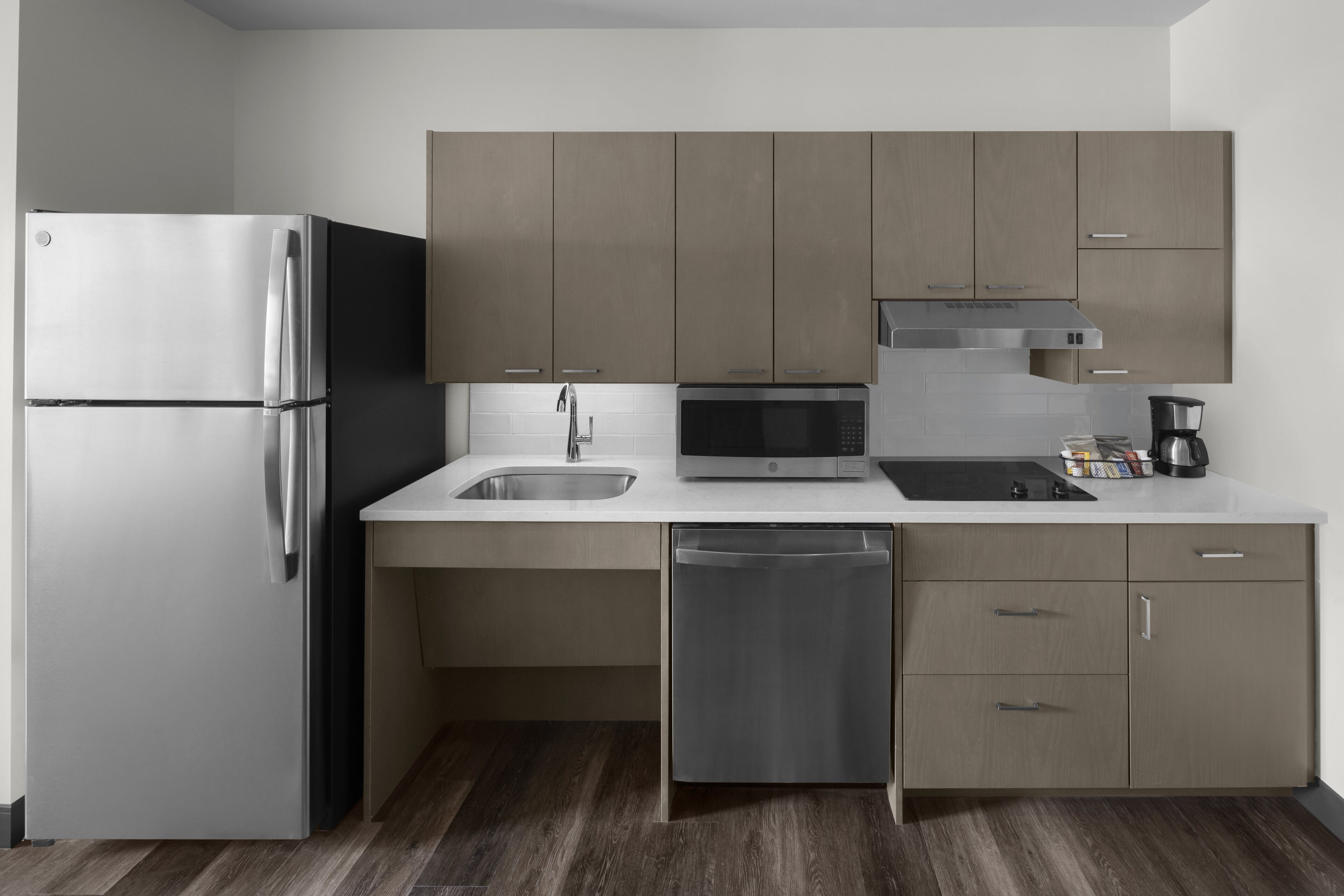 A modern kitchen with stainless steel appliances, a dishwasher, and wooden cabinets.