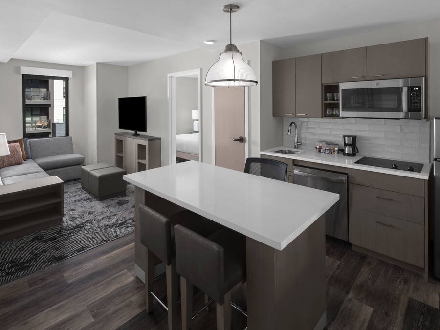 Una habitación de hotel moderna con kitchenette, un sofá, un televisor y un comedor.