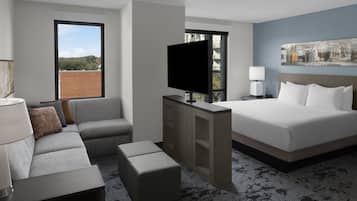 A hotel room with a large bed, a sofa, a TV, and a desk.