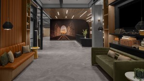 Een moderne lobby met een houten wand, een groene bank en een receptiebalie.