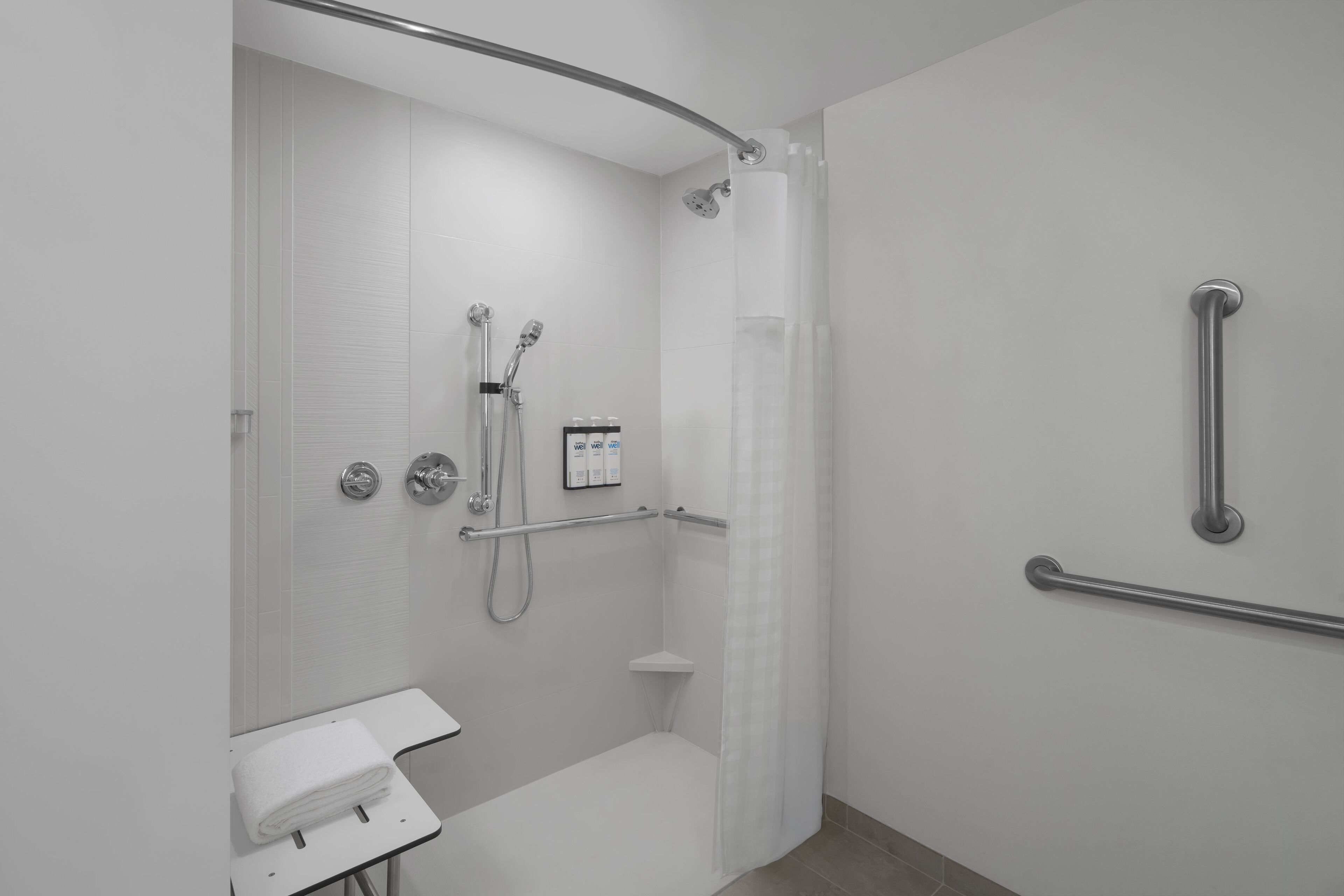 A modern bathroom with a shower, grab bars, and a toilet.