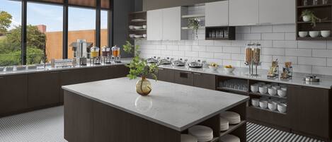 A modern kitchen with a central island, white cabinets, and a view of the outdoors.
