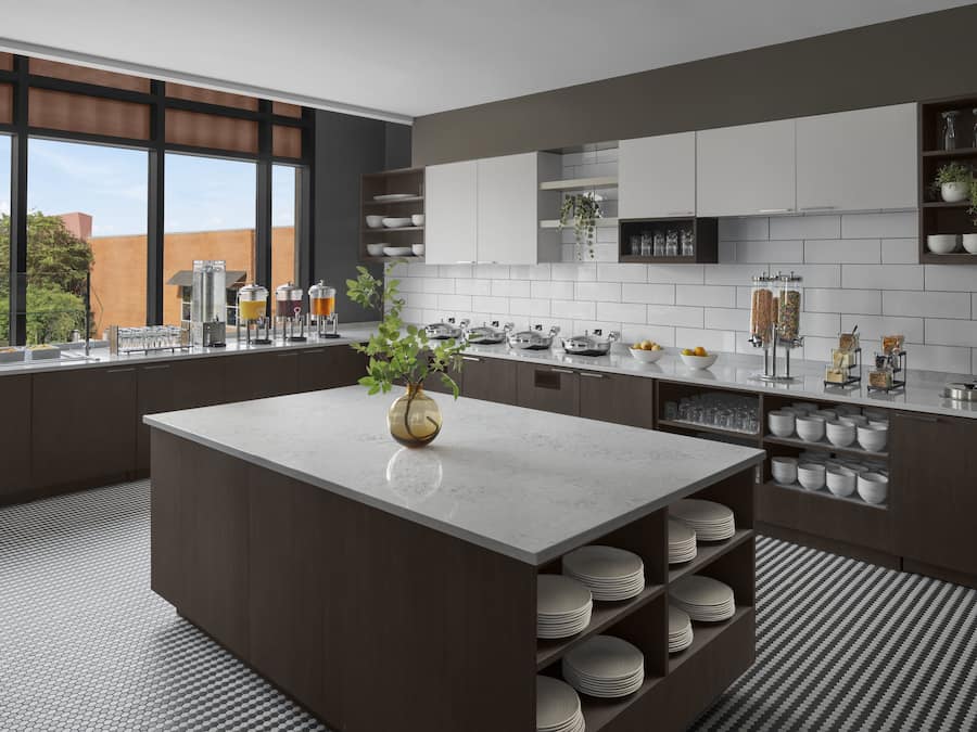 Una cocina moderna con una isla central, armarios blancos y vistas al exterior.