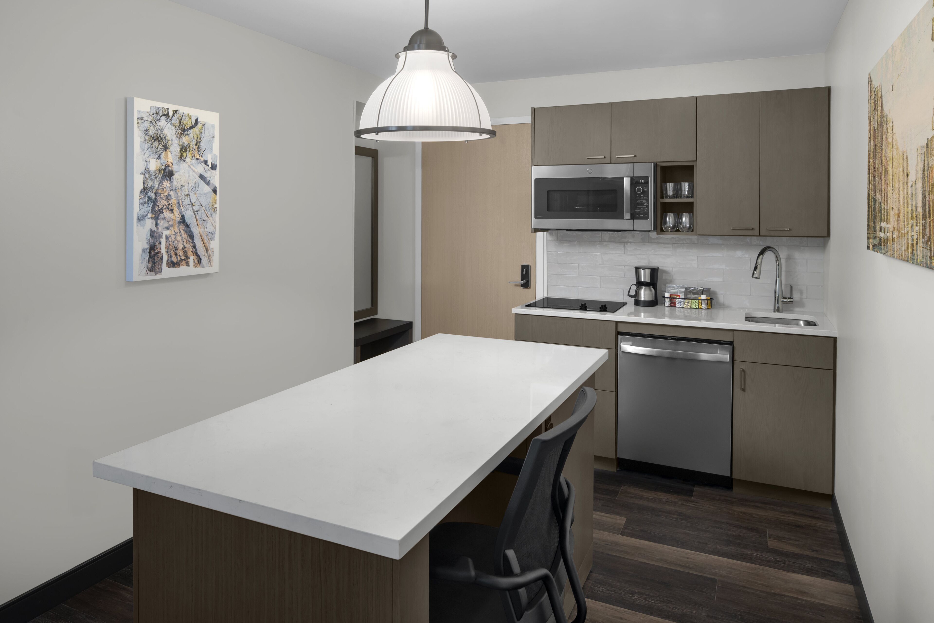 A modern kitchen with a central island, stainless steel appliances, and a pendant light.