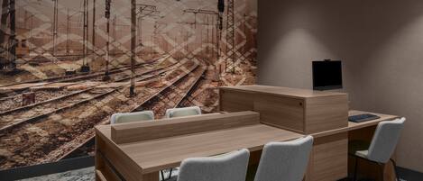 Un bureau moderne avec un grand bureau en bois, plusieurs chaises et une grande fresque murale représentant des voies ferrées.