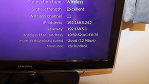 Ein Samsung-Monitor zeigt eine Wi-Fi-Verbindungsanzeige mit Details wie Signalstärke, IP-Adresse und Downloadgeschwindigkeit.