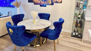 A dining area with a round table, blue upholstered chairs, and a glass cabinet with bottles. - Luxury Home with Hot Tub, a stunning haven with 3 bedrooms and 2.5 bath (Calgary)