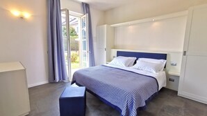 Une chambre à coucher comprenant un lit, une table de chevet, une commode et une fenêtre avec des rideaux.