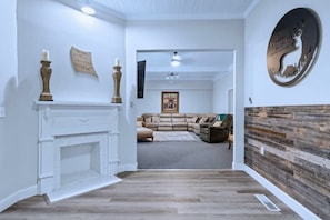 A modern living room with a fireplace, a sectional sofa, and a decorative wall piece. - Tranquil 7-Bed Retreat
 (Sumner)