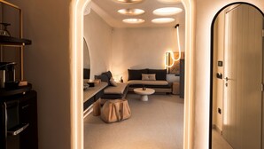 A modern hotel room with a sofa, a coffee table, a desk with a lamp, and a wardrobe. - Brilliant Topaz Suite with Private Pool (Mykonos)