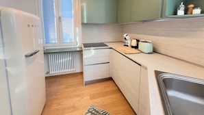 A compact kitchen with a refrigerator, a toaster, and a coffee maker on the counter. - Villa Ada al Lido (Venice)