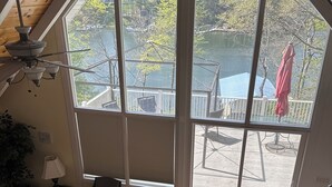 Ein geräumiges Wohnzimmer mit großem Fenster und Blick auf einen See sowie eine Terrassenfläche.