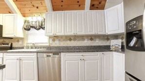 Eine Küche mit weißen Schränken, einer Granitarbeitsplatte und einem Edelstahlkühlschrank.