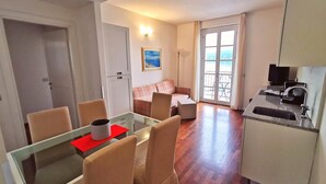 Eine moderne Wohnung mit Essbereich, Wohnzimmer mit Sofa, Balkon und einer Küchenzeile.