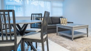 A modern living room with a dining table, chairs, a sofa, and a coffee table.
