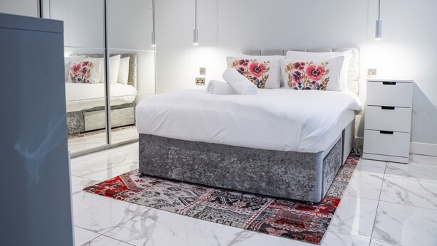 A modern bedroom with a large bed, a bedside table, and a mirror.