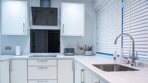 A modern kitchen with white cabinets, a stainless steel sink, and a built-in oven.