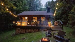Eine rustikale Holzhütte mit einer Terrasse, Sitzgelegenheiten im Freien und einer Feuerstelle.