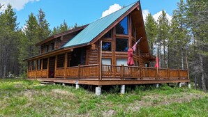 Una cabaña de troncos con balcón, rodeada de bosque.